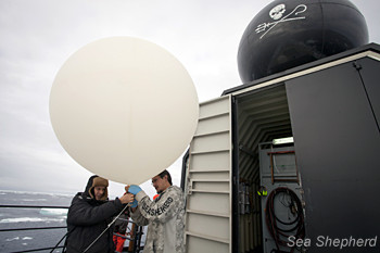 Crewmembers prepare the surveillance weather balloons for launch.
